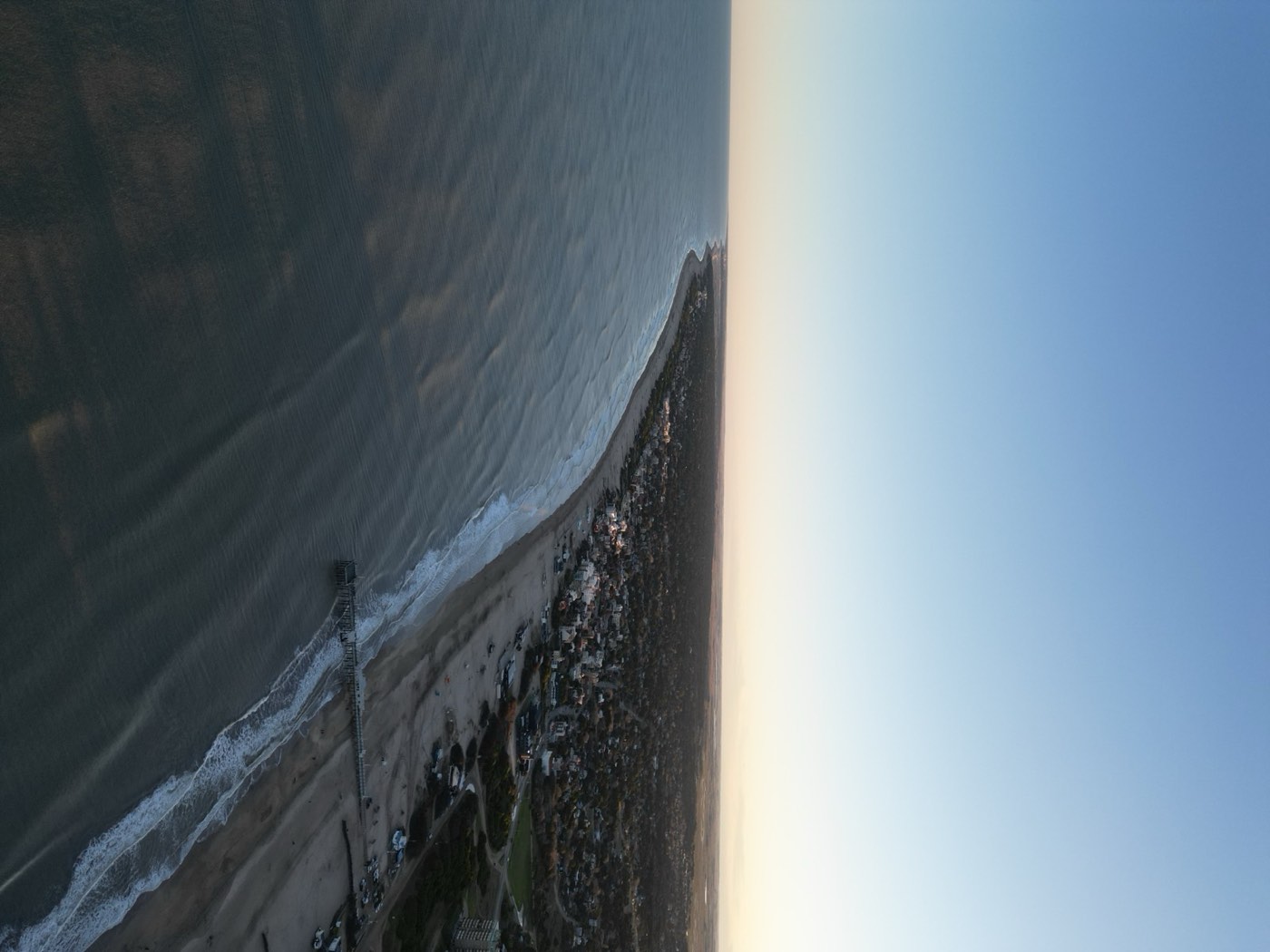 Atardecer sobre la costa de Pinamar con el muelle de pesca, fotografía aérea con drone